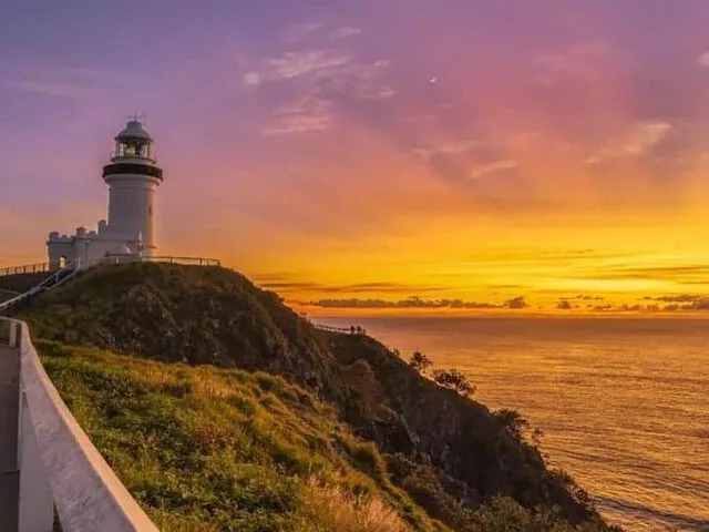 Un faro se alza sobre un acantilado al atardecer con un hermoso cielo.