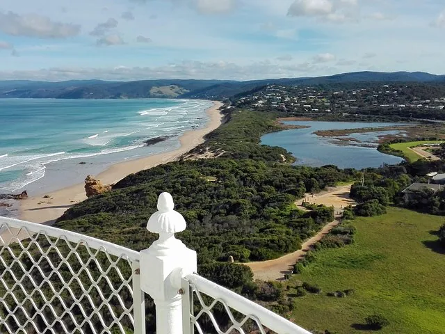 View from a lighthouse looking over a coastal landscape and beach.