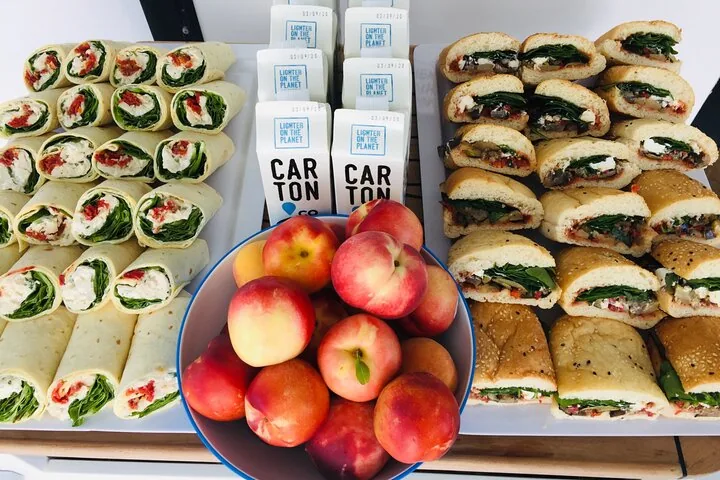 Una selección de wraps, cartones de agua y melocotones frescos sobre una mesa.