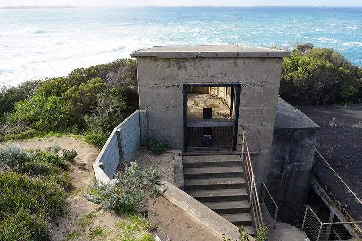 An old concrete bunker structure on a cliff overlooking the ocean.