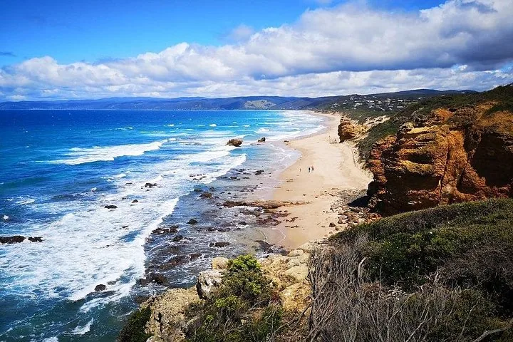Eine malerische Küste mit einem Sandstrand und brechenden Wellen neben Klippen.