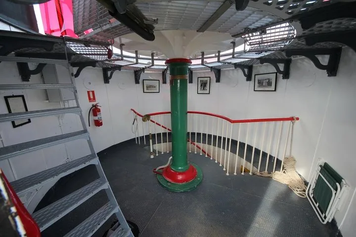 Das Innere eines Leuchtturms mit einer grünen Mittelsäule und einer Treppe.