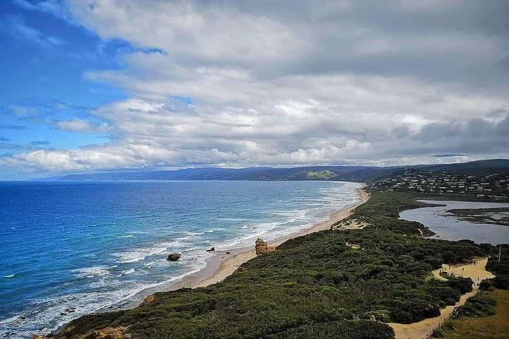 Vista expansiva de una costa con olas rompiendo en una larga playa de arena.